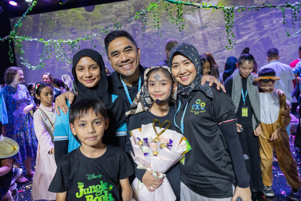Learner celebrating with family members following The Jungle Book Primary School production at Nexus International School Malaysia.
