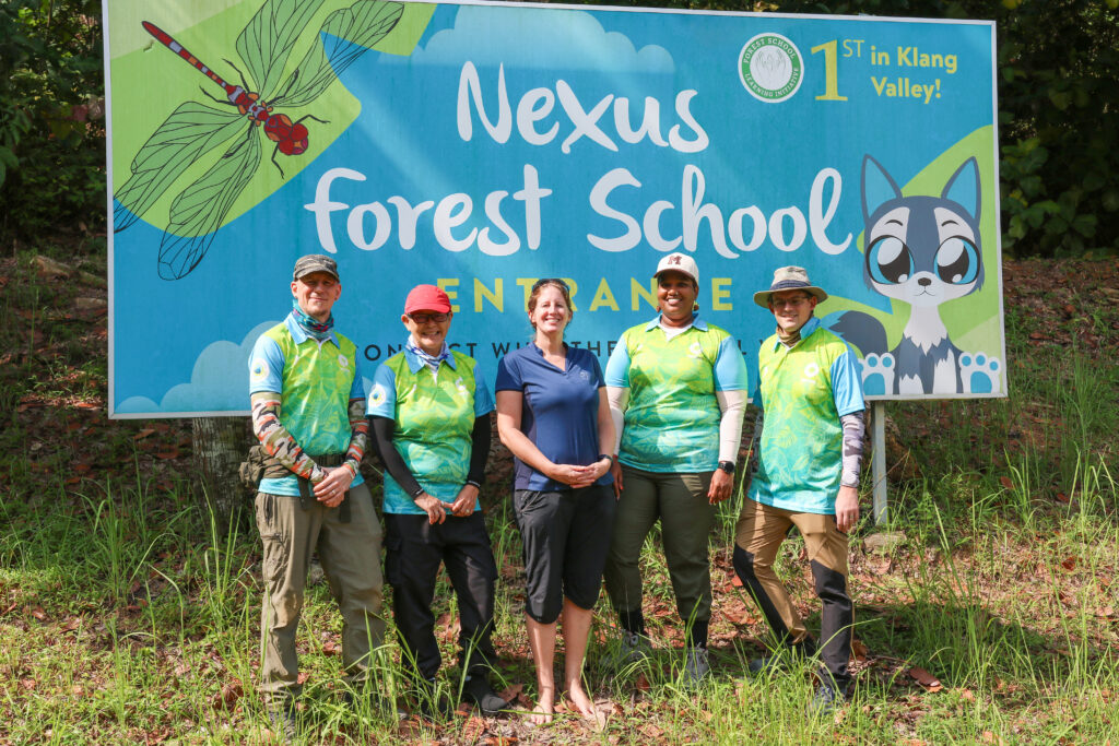 The Nexus Forest School team standing at the Forest School entrance at Nexus International School Malaysia.